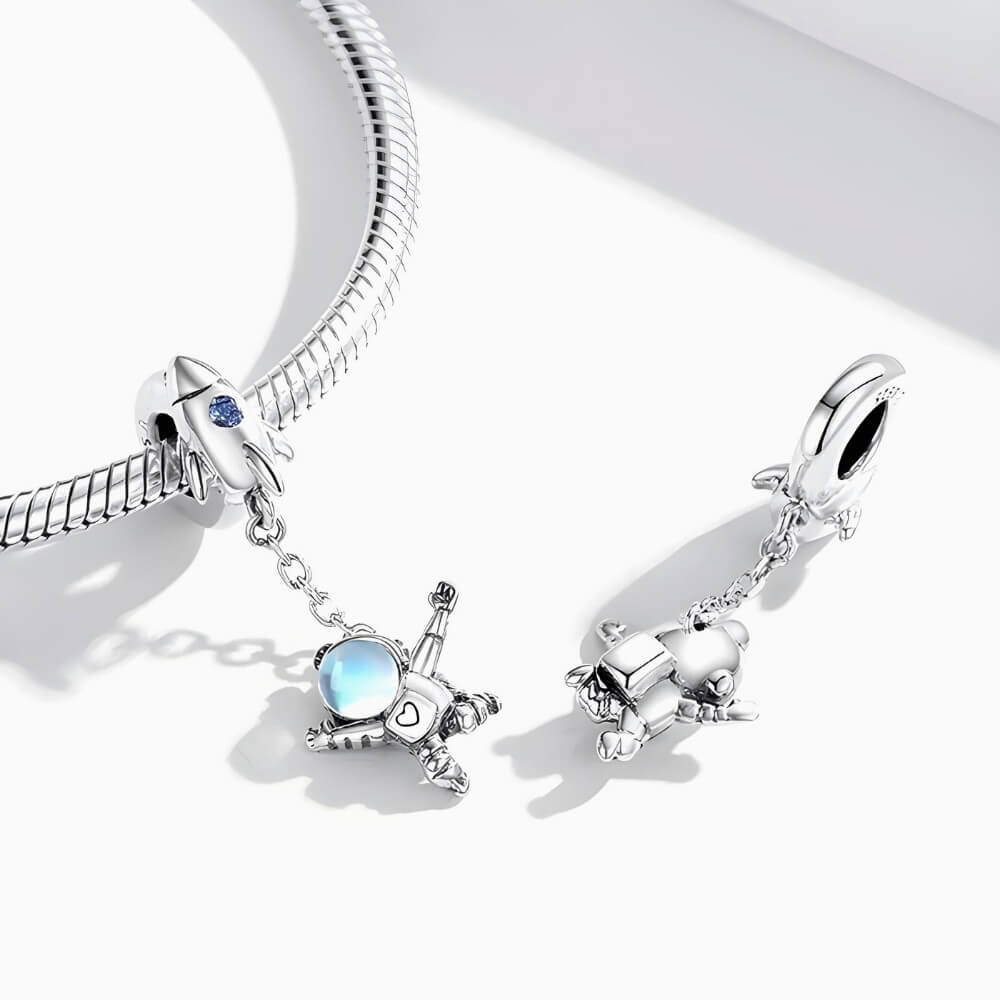 Sterling silver astronaut charm hanging from rocket bail with blue glass visor.