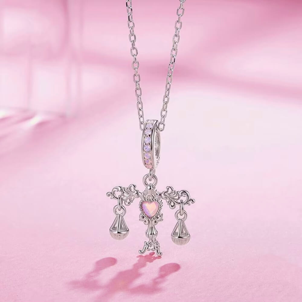 Sterling silver balance charm with opal heart center and hanging scales.
