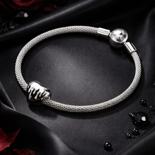 Sterling silver heart charm with black enamel flame design.