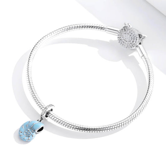 Sterling silver nautilus shell charm with blue enamel and clear gemstones.