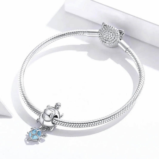 Sterling silver turtle charm with baby turtle detail and soft blue glass accent.