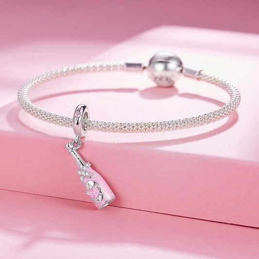 Sterling silver champagne bottle charm with pink enamel, bow detail and heart crystal.