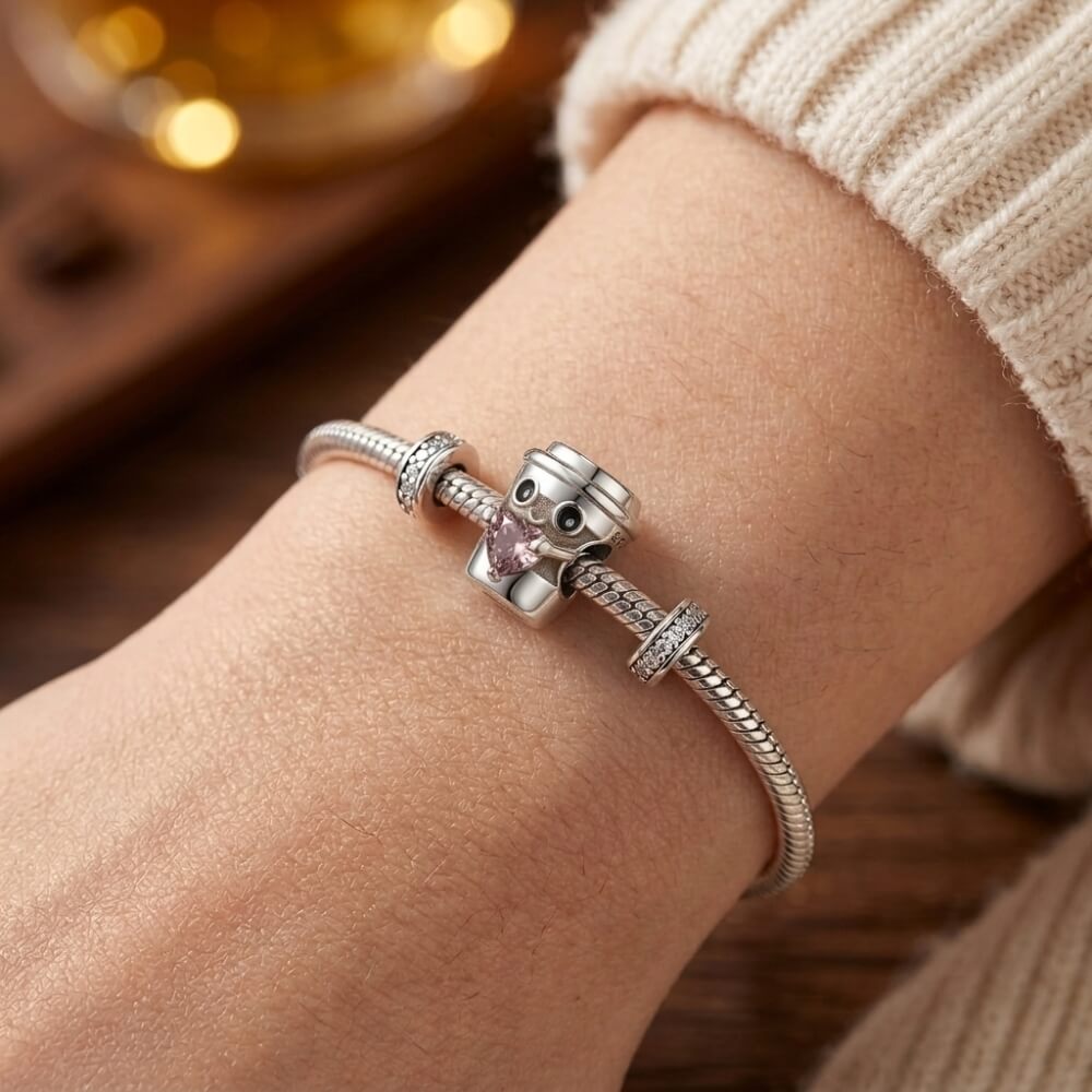 Sterling silver coffee cup charm holding pink heart crystal.