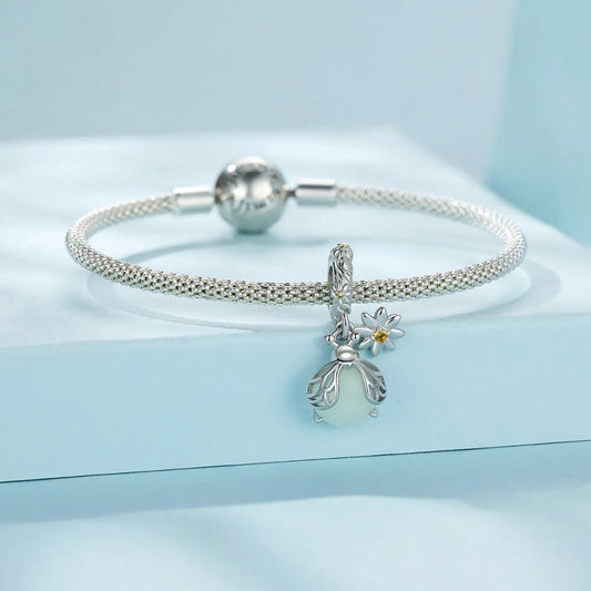 Sterling silver firefly charm with mint glowing enamel body and yellow flower detail.