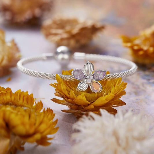 Sterling silver flower charm with lavender petals and iridescent crystal details.