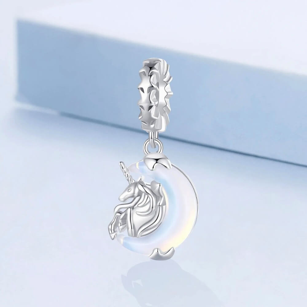 Sterling silver unicorn charm on moon with opalescent glow.