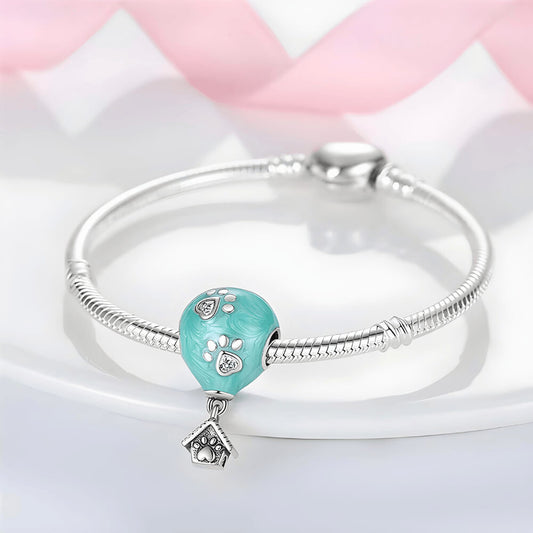 Turquoise balloon-shaped charm with silver paw prints and dangling dog house