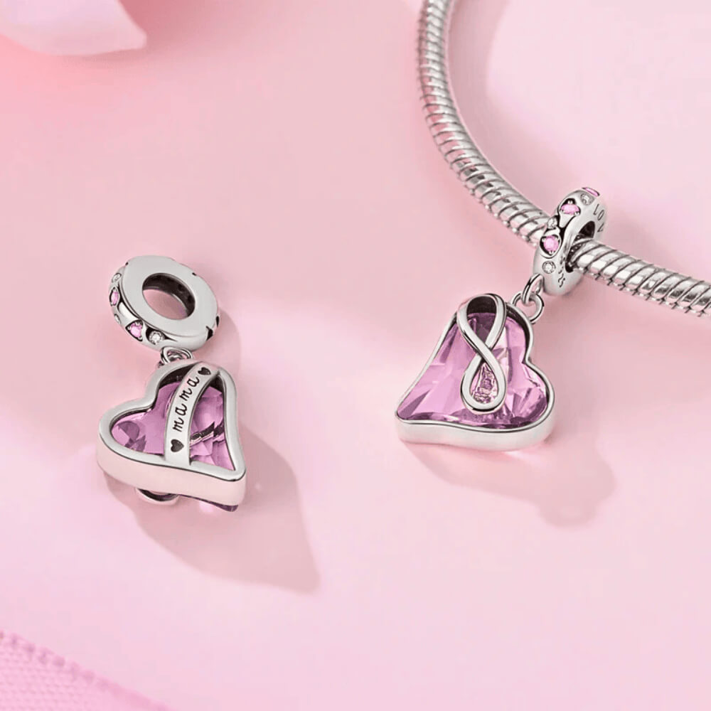 Sterling silver dangle charm with a faceted light-pink crystal heart wrapped in an infinity symbol and pink heart stones on the bail
