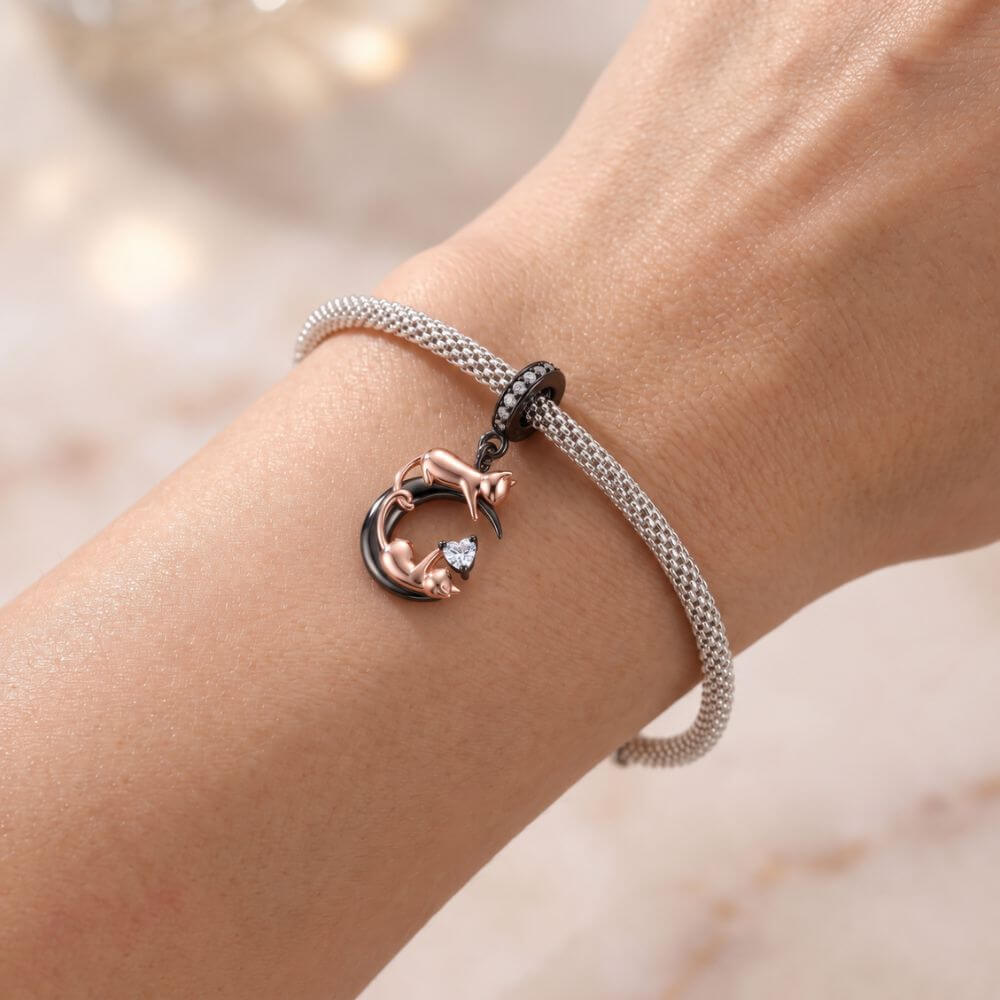 Rose gold cat moon charm with two playful cats, black crescent moon, and sparkling heart crystal detail.