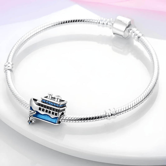 Sterling silver cruise-ship charm with blue enamel waves, blue crystal details on the upper deck, and a dangling anchor with a blue stone