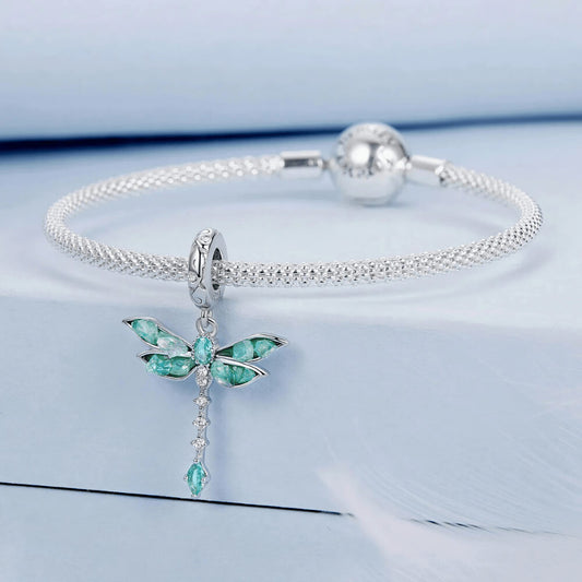 Sterling silver dragonfly charm with blue-green iridescent enamel wings, sparkling clear stones, and a teardrop blue crystal tail