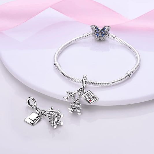 Sterling silver charm with a crystal-studded Eiffel Tower, a small airplane with clear stones, and an engraved postcard