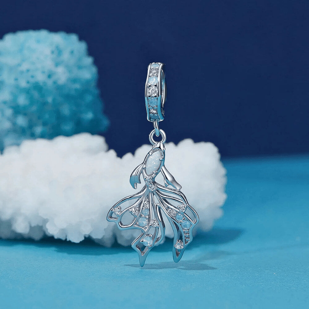 Sterling silver fish charm with opal-like stone and blue gemstone accents.