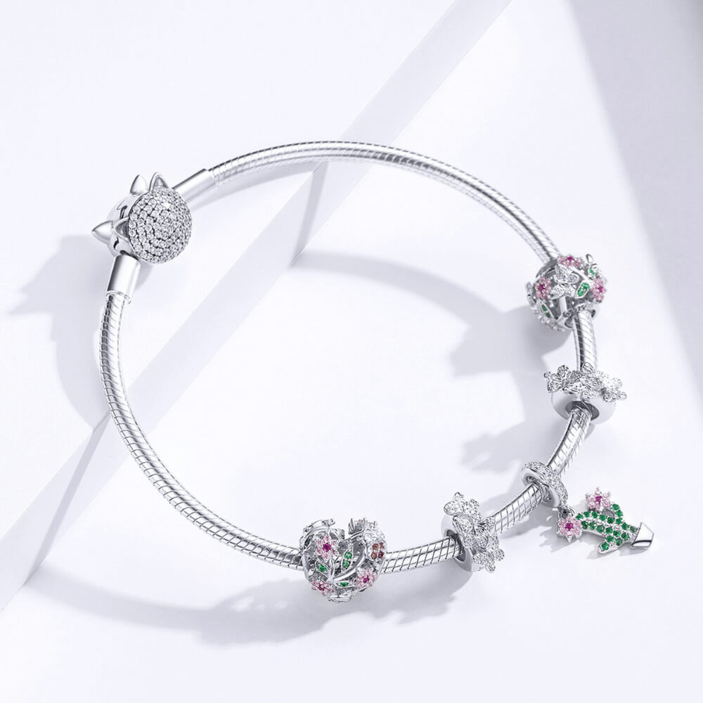 Sterling silver openwork charm with pink crystal flowers, green crystal leaves, and silver butterflies with clear stones