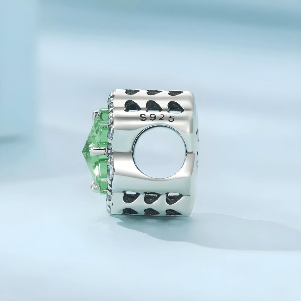 Sterling silver charm with a large green four-petal faceted stone framed by clear crystals
