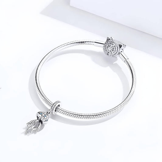 Sterling silver jellyfish charm with blue stones on the bell and long flowing tentacles, hanging from a bail set with clear crystals