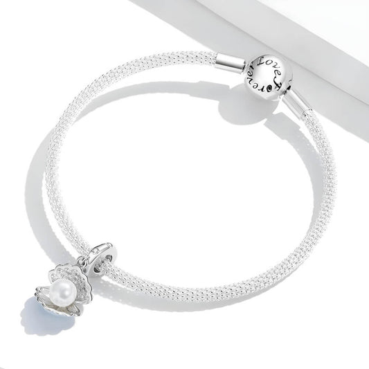 Sterling silver seashell charm with clear gemstones and a dangling white pearl bead.