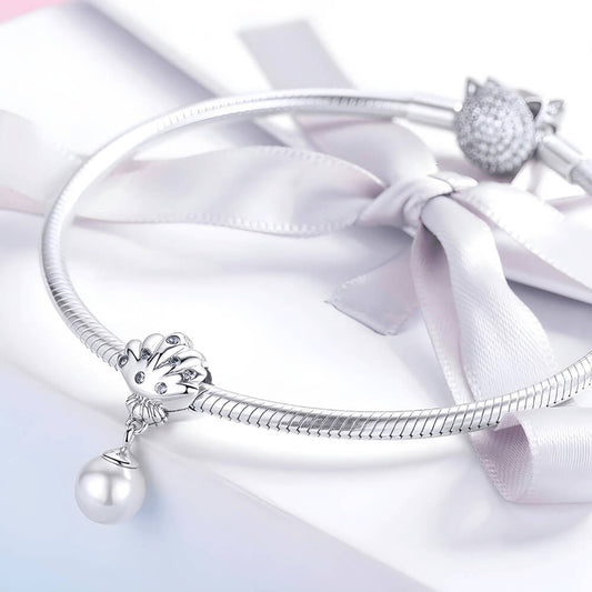 Sterling silver shell charm with blue gemstones and a dangling white pearl.