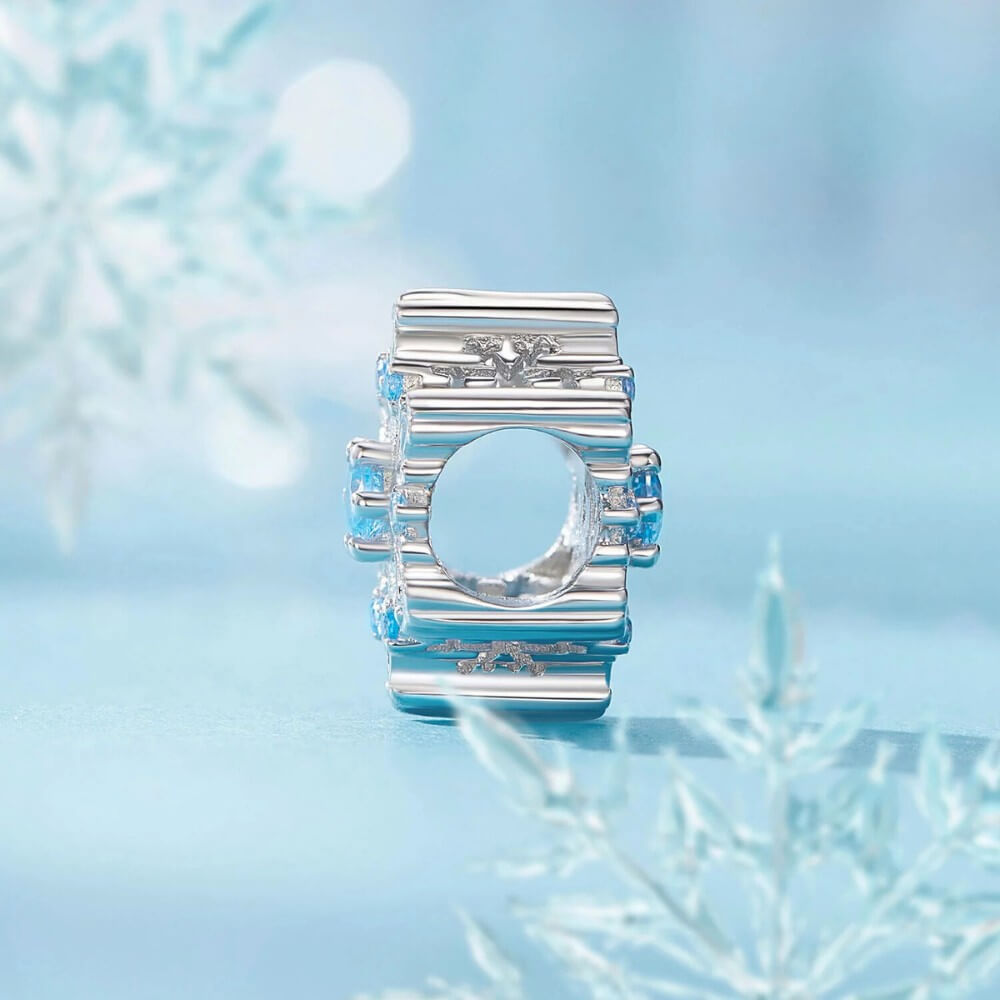 Sterling silver snowflake charm with detailed openwork design and light blue gemstones.