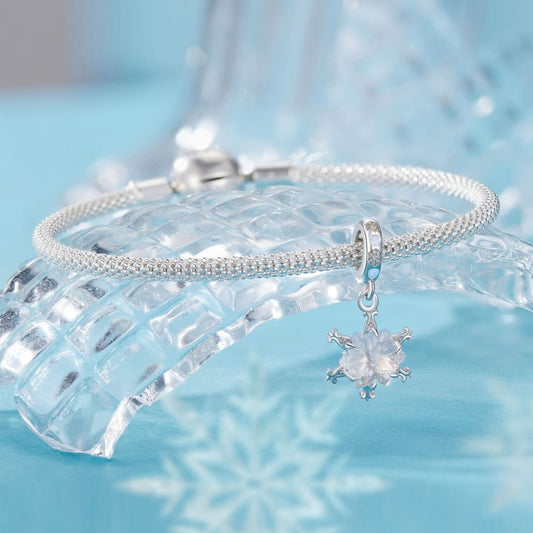 Sterling silver snowflake charm with iridescent crystal and blue accents.