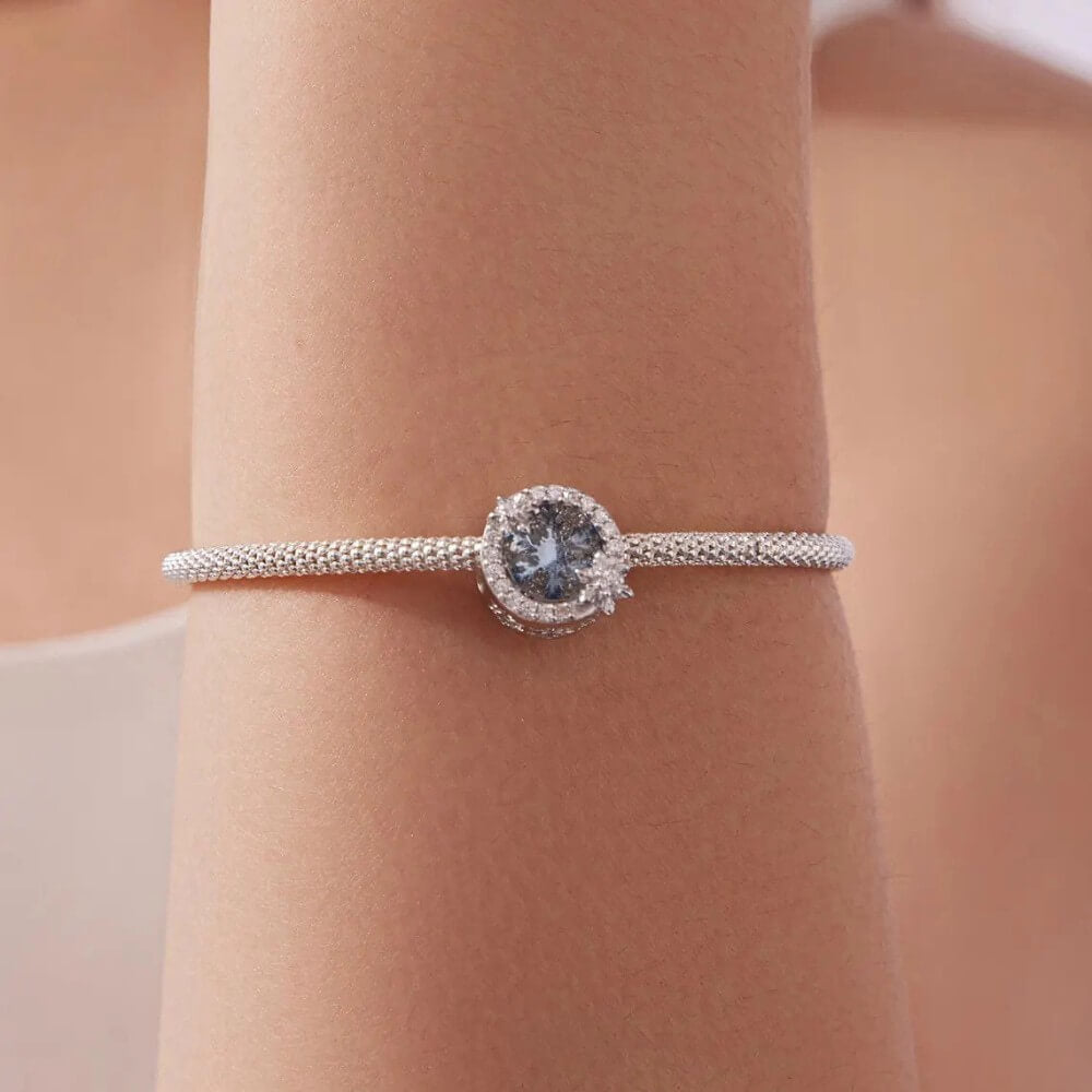 Sterling silver snowflake charm with icy crystal center and pavé details.