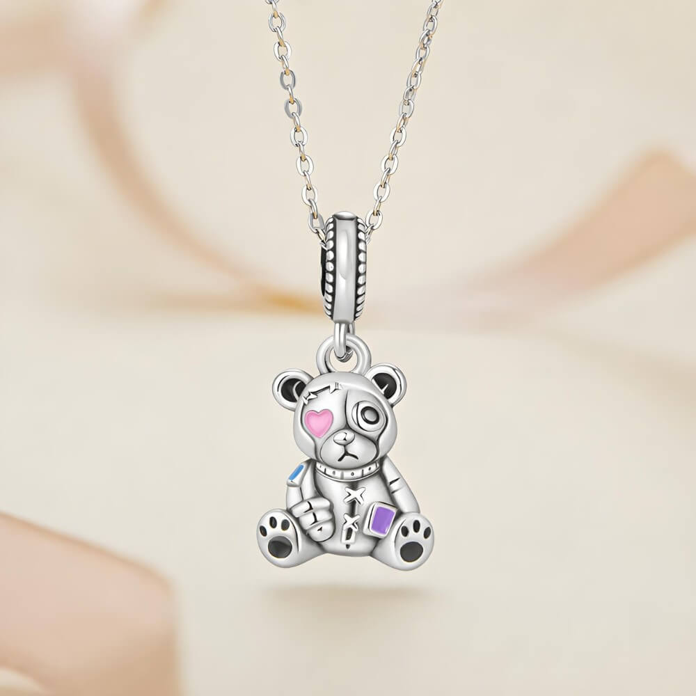Sterling silver teddy bear charm with stitched details and enamel accents.