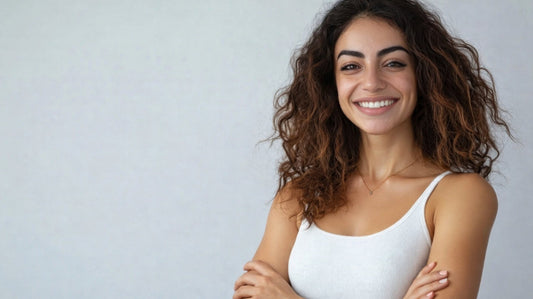 Smiling woman with curly hair standing against a neutral background