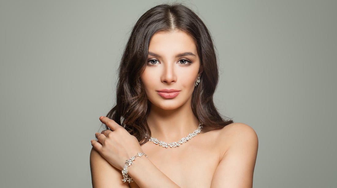 Woman wearing a silver necklace and matching bracelet against a neutral background