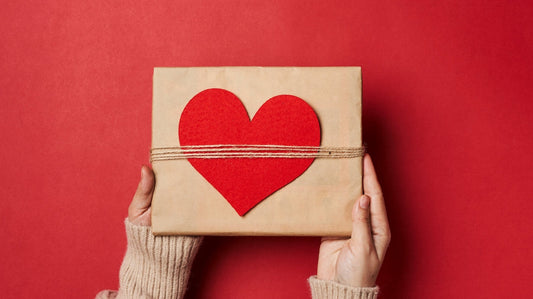 Hands holding a wrapped gift box with a red heart on the front