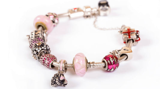 Charm bracelet with mixed silver and pink charms, showing how to start a charm bracelet with meaningful pieces