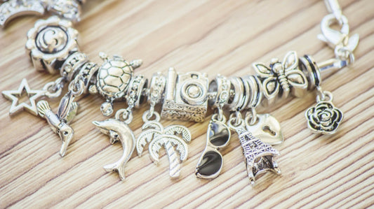 Charm bracelet with multiple silver charms displayed on a wooden surface
