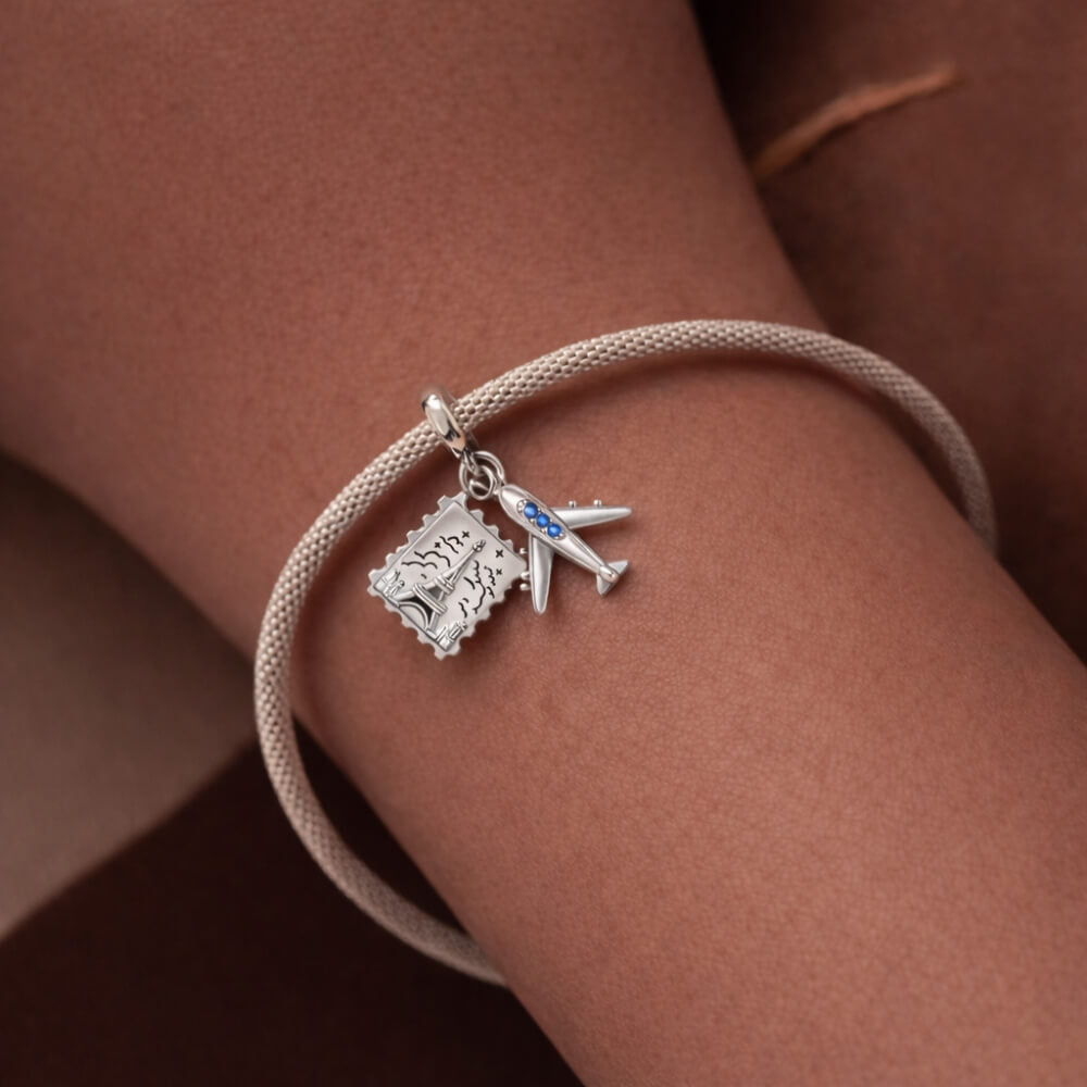 Sterling silver airplane and postcard charm with blue crystal accents.