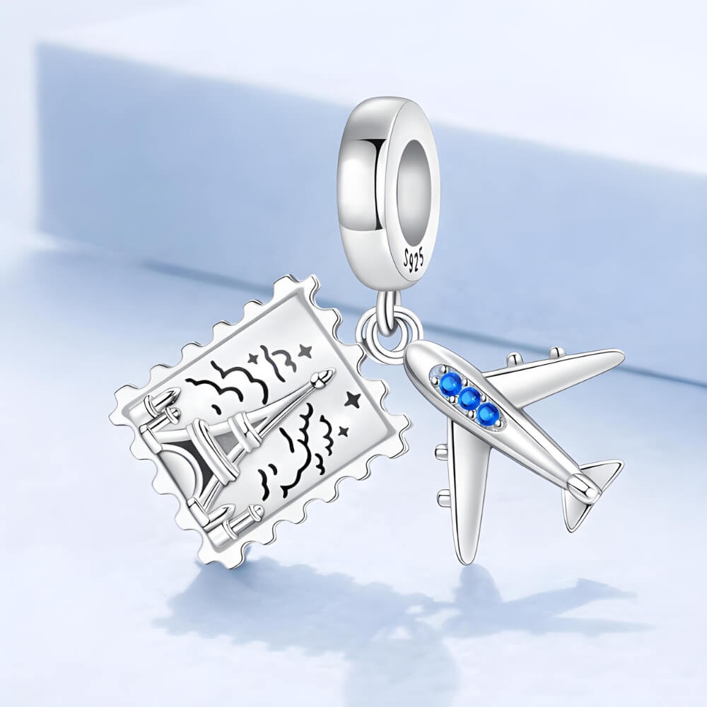Sterling silver airplane and postcard charm with blue crystal accents.