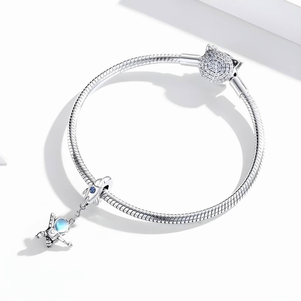Sterling silver astronaut charm hanging from rocket bail with blue glass visor.