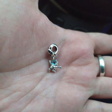 Sterling silver astronaut charm hanging from rocket bail with blue glass visor.