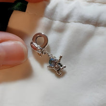 Sterling silver astronaut charm hanging from rocket bail with blue glass visor.