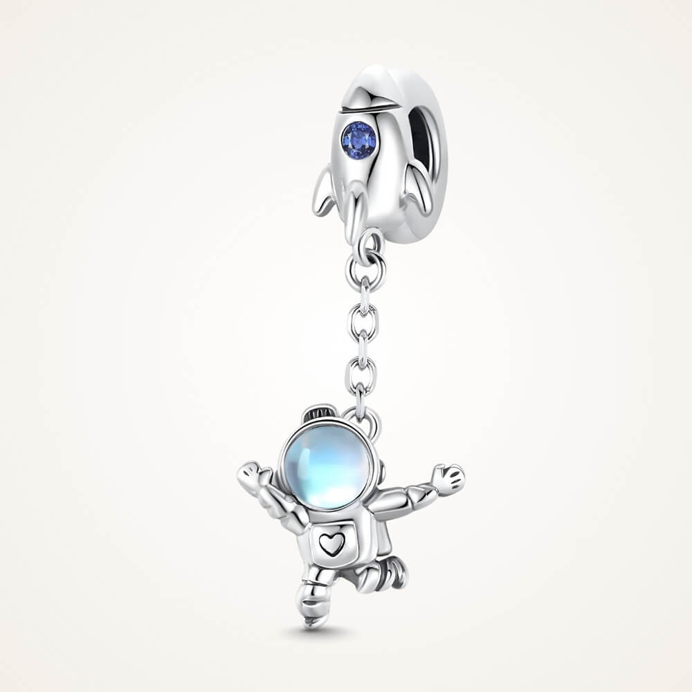 Sterling silver astronaut charm hanging from rocket bail with blue glass visor - ORÉYA