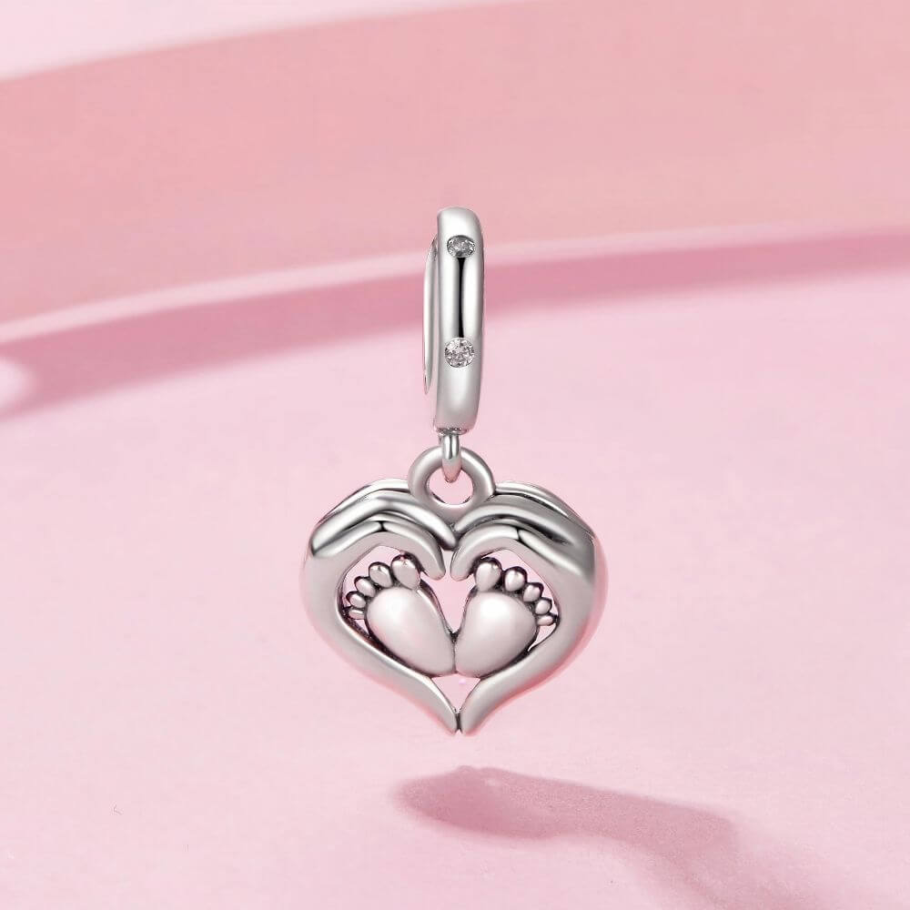 Sterling silver baby feet charm framed by a heart with sparkling crystal accents and delicate polished details.