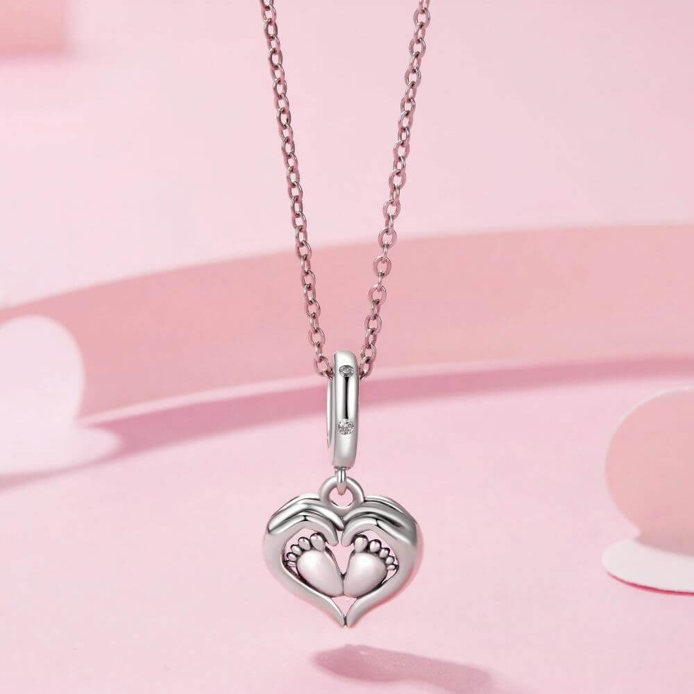 Sterling silver baby feet charm framed by a heart with sparkling crystal accents and delicate polished details.