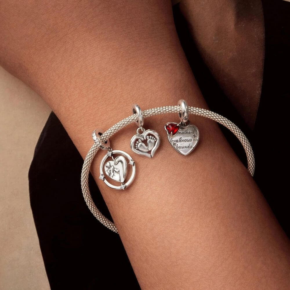 Sterling silver baby feet charm framed by a heart with sparkling crystal accents and delicate polished details.