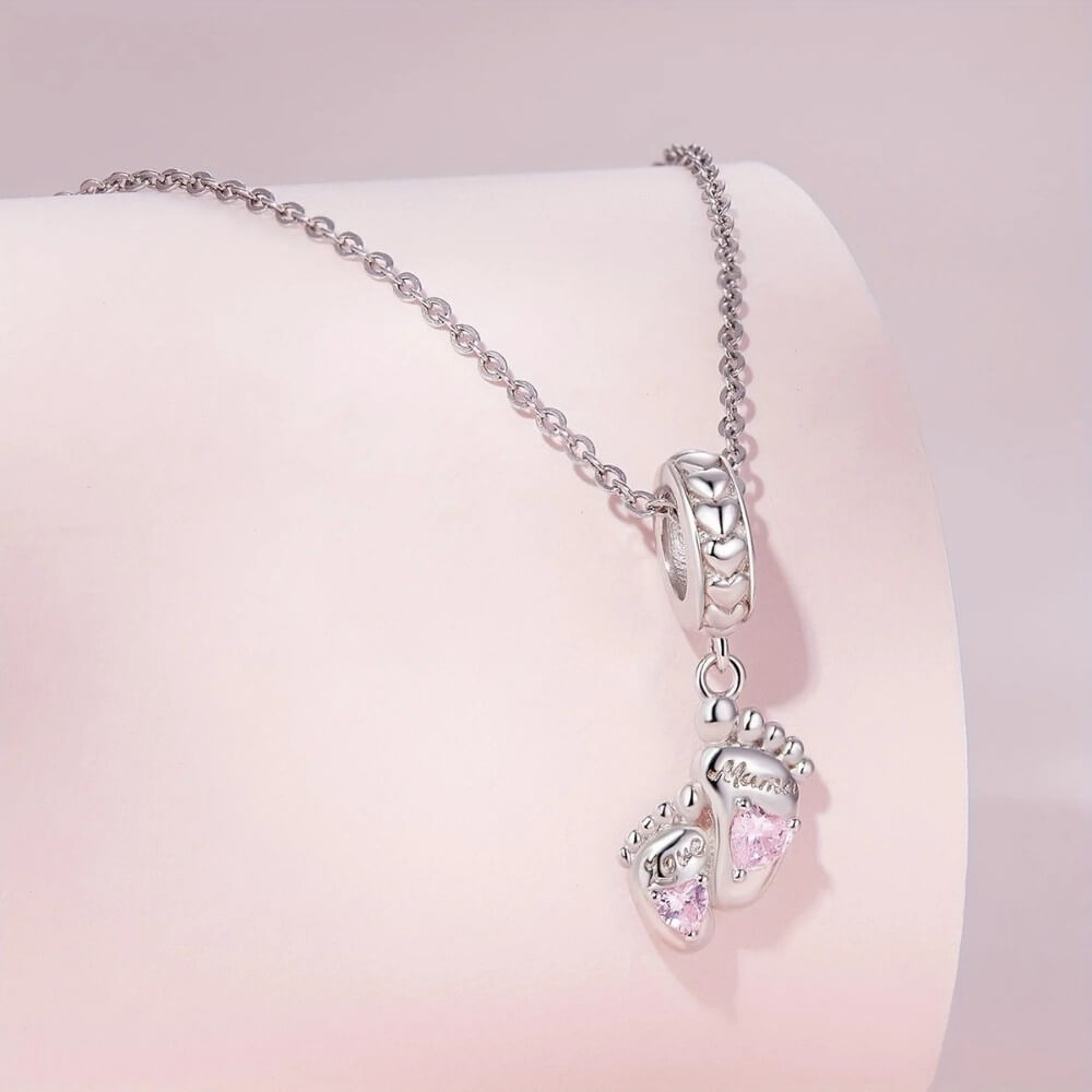 Sterling silver baby feet charm with pink heart crystals and mom engraving.