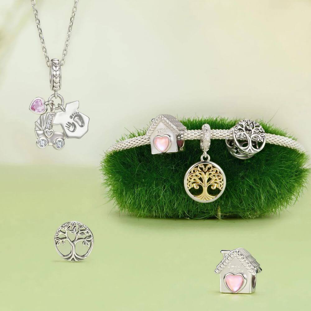 Silver jewelry set with tree of life and house charms, including a necklace, bracelet, earrings, and charm pieces, displayed on a light green background with a green fuzzy cushion.