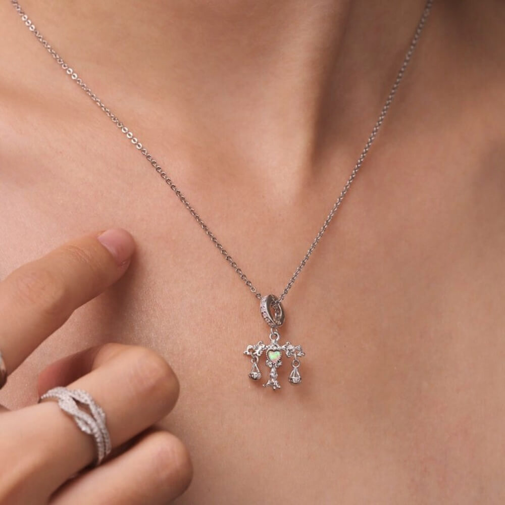 Sterling silver balance charm with opal heart center and hanging scales.