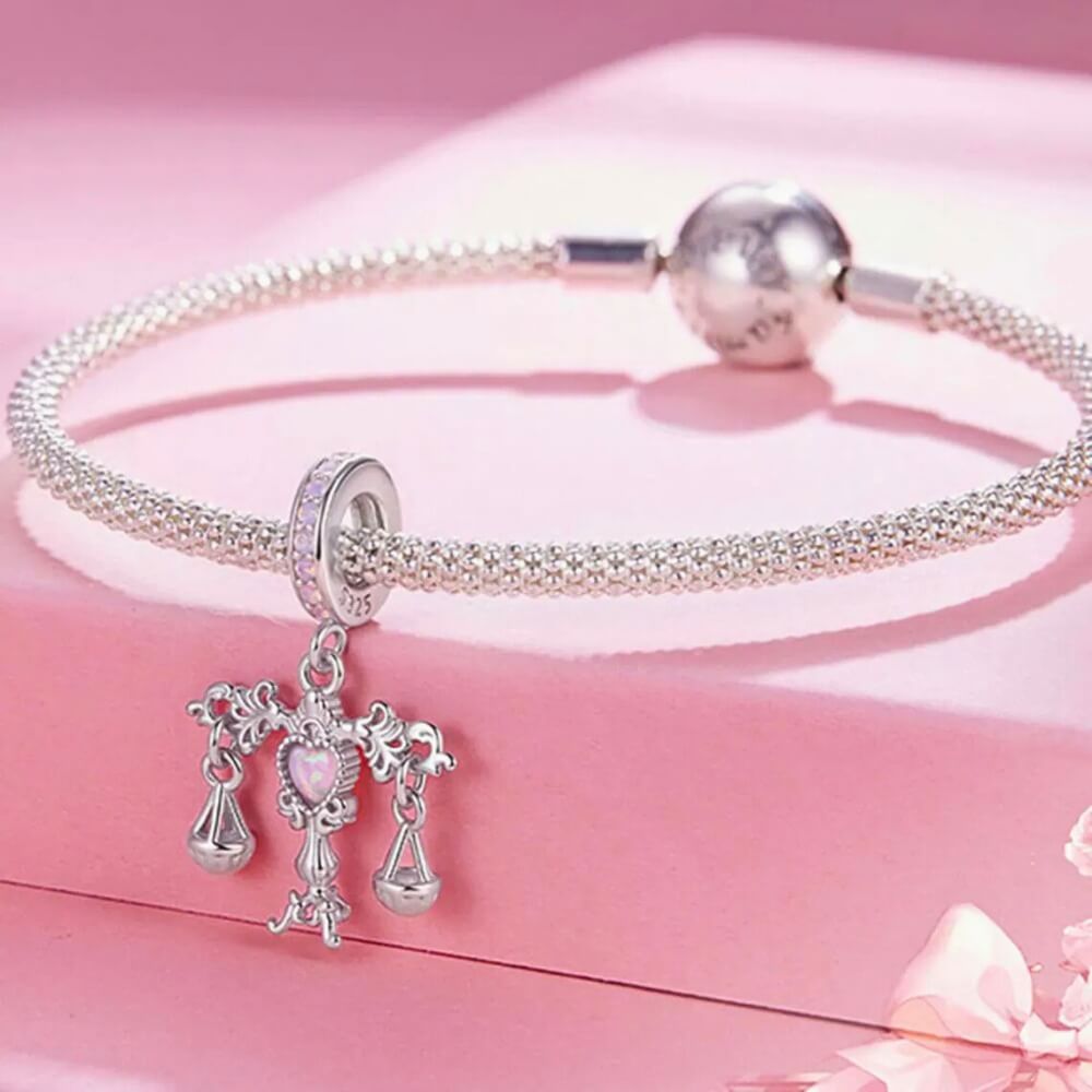 Sterling silver balance charm with opal heart center and hanging scales.