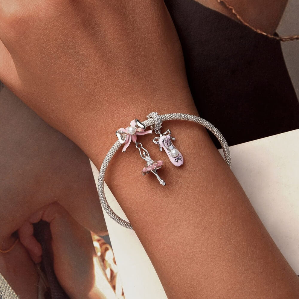 Sterling silver ballerina charm with pink enamel bow and crystal accents.