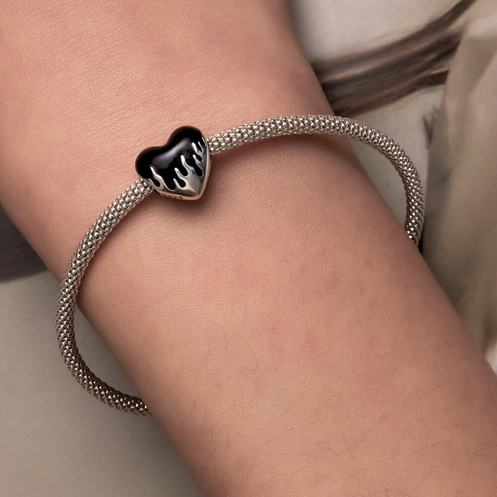 Sterling silver heart charm with black enamel flame design.