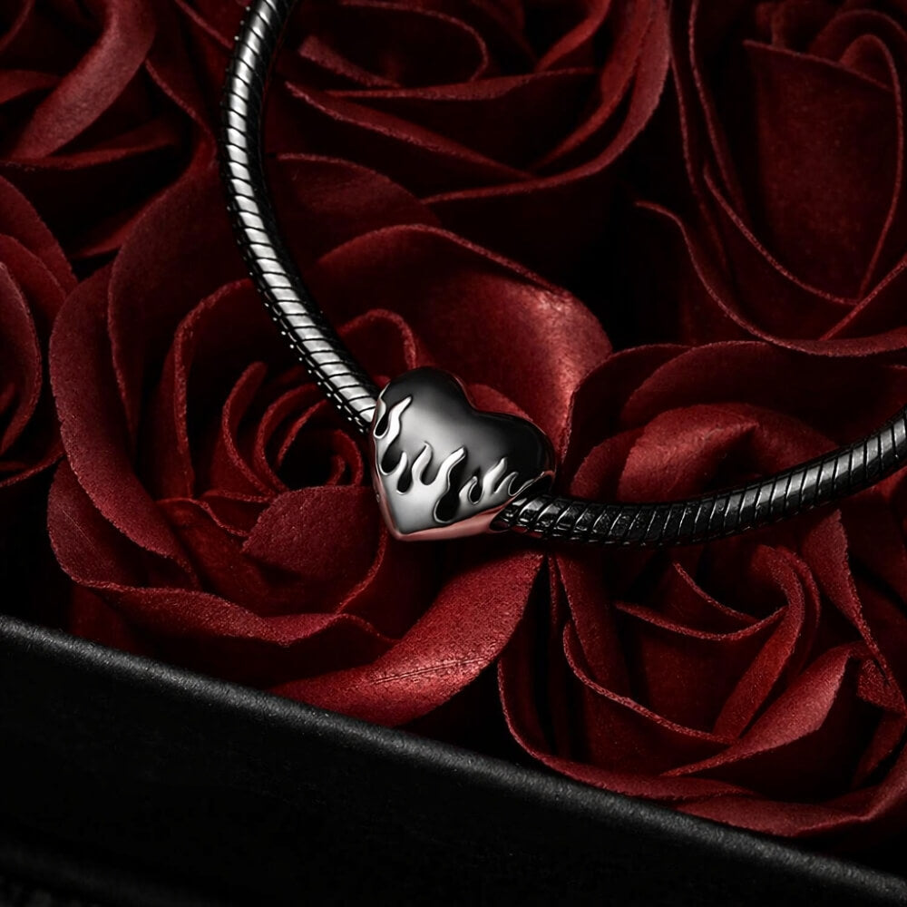 Sterling silver heart charm with black enamel flame design.