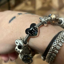 Sterling silver heart charm with black enamel flame design.