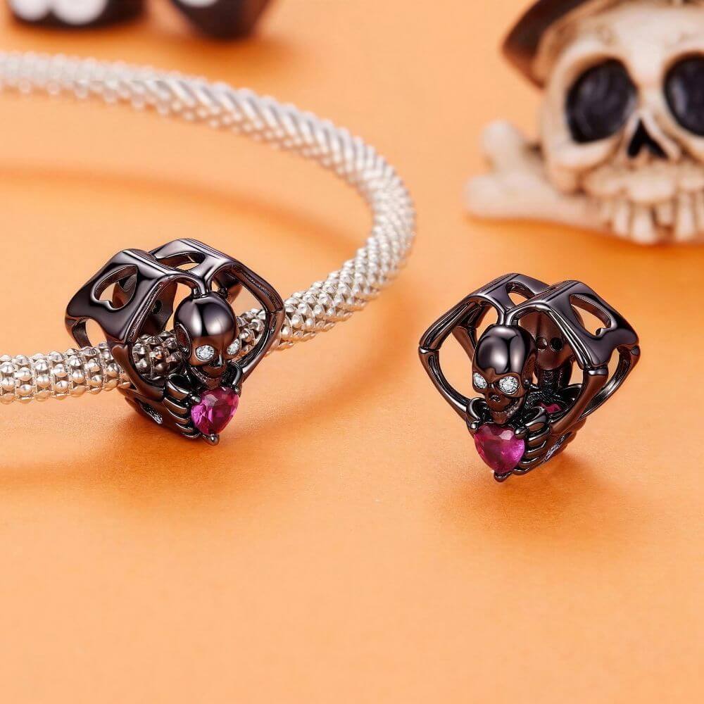 Black skeleton heart charm with crystal eyes, vivid pink heart stone, and gothic skeletal arm details.