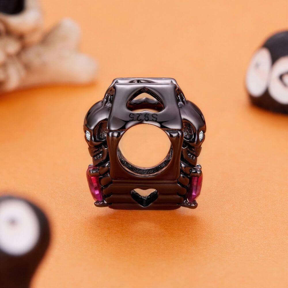 Black skeleton heart charm with crystal eyes, vivid pink heart stone, and gothic skeletal arm details.